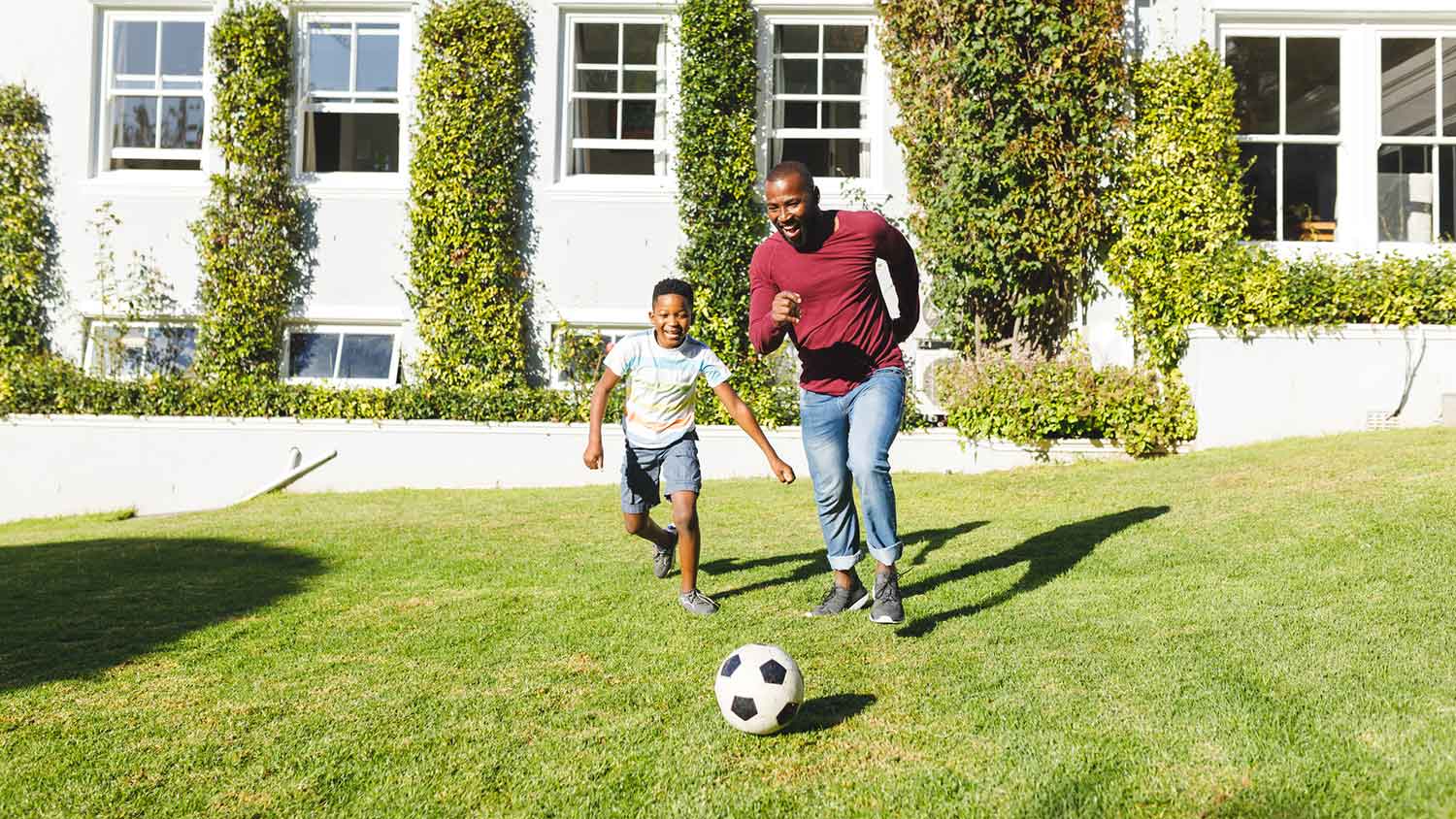 Father and son playing soccer in the yard