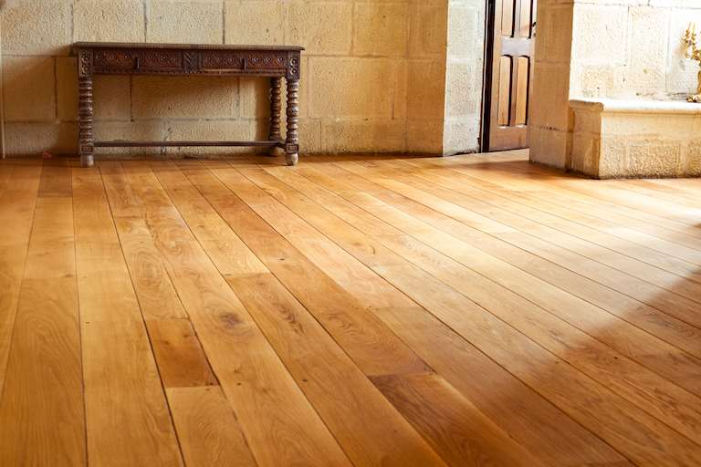 Closeup of wide plank, golden yellow wood floor with console table