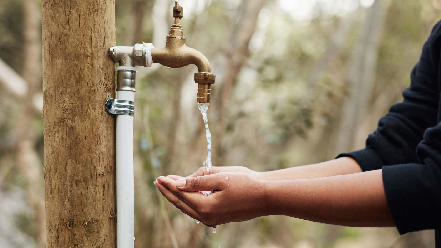 A woman washing her hands in a hose bib