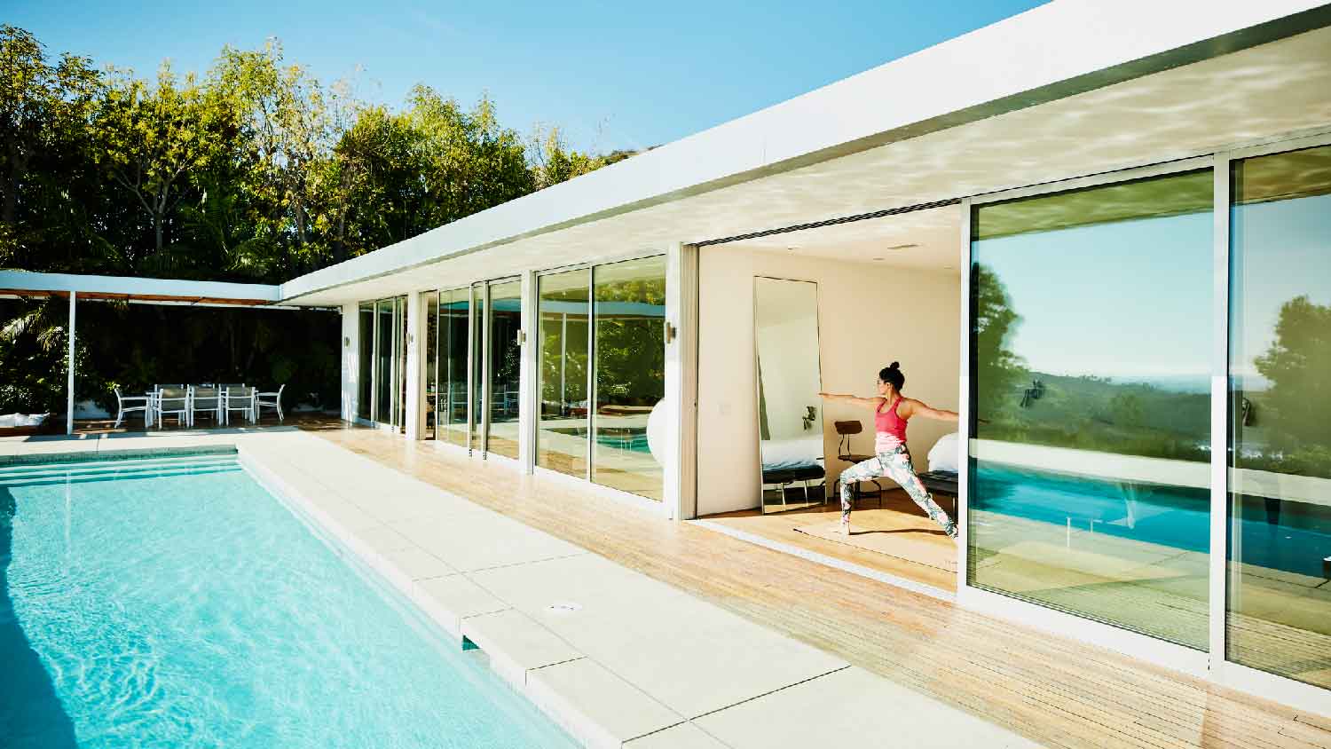 A woman doing her yoga practice in front of the pool