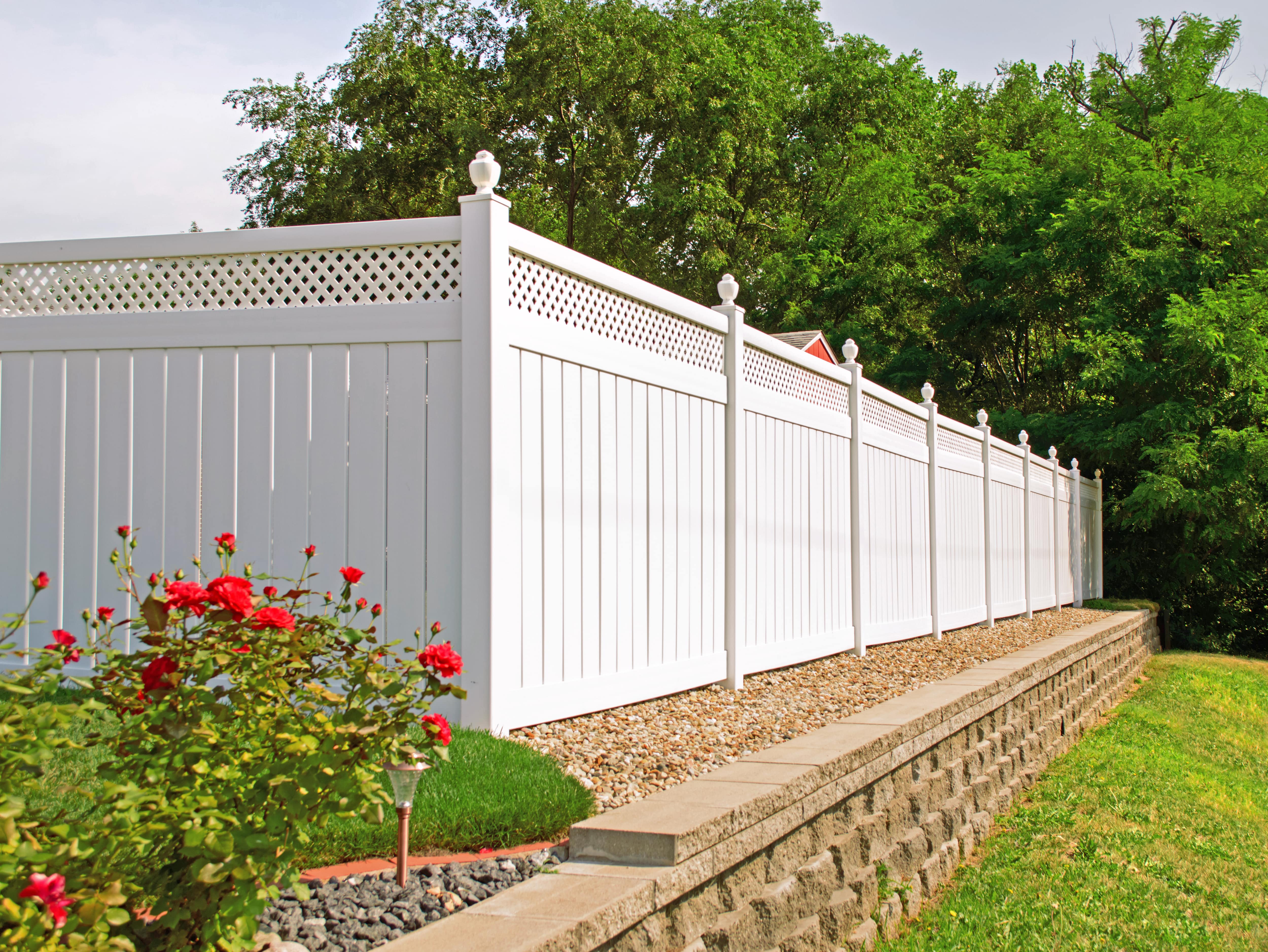 A white vinyl fence enclosing a residential backyard