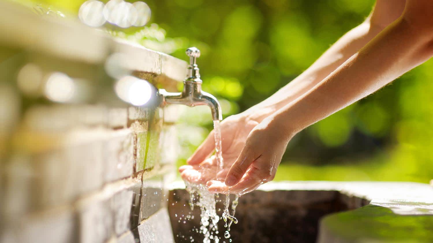 A woman washing her hands in a spigot