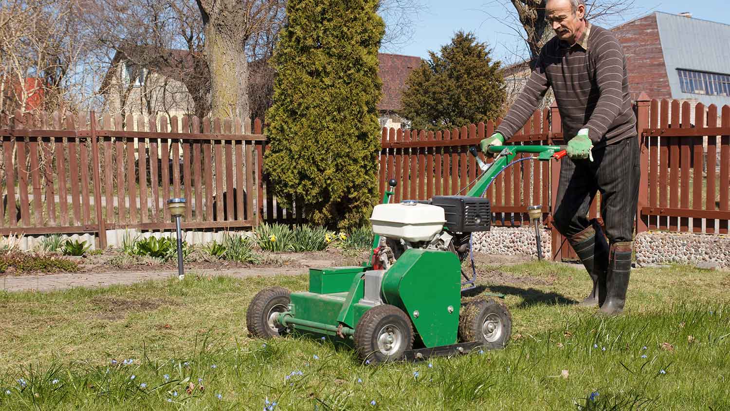 Man using aerator in his yard to break up the soil