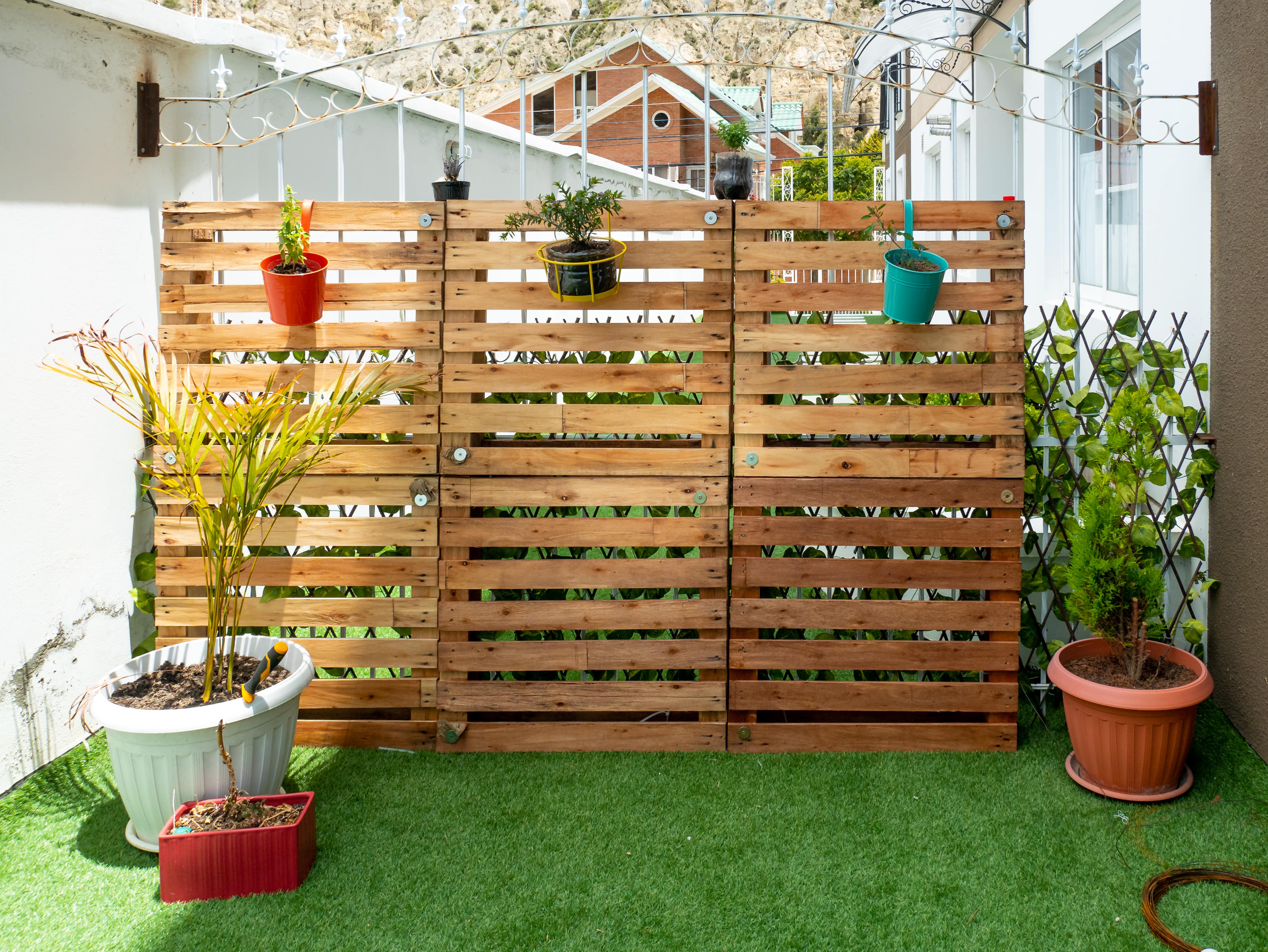 A wood pallet privacy fence with hanging plants on the porch
