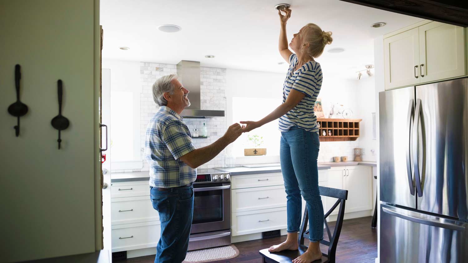 father helping daughter change recessed light bulb
