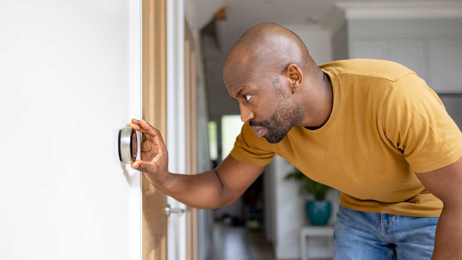 Man adjusting the temperature on the thermostat of his house