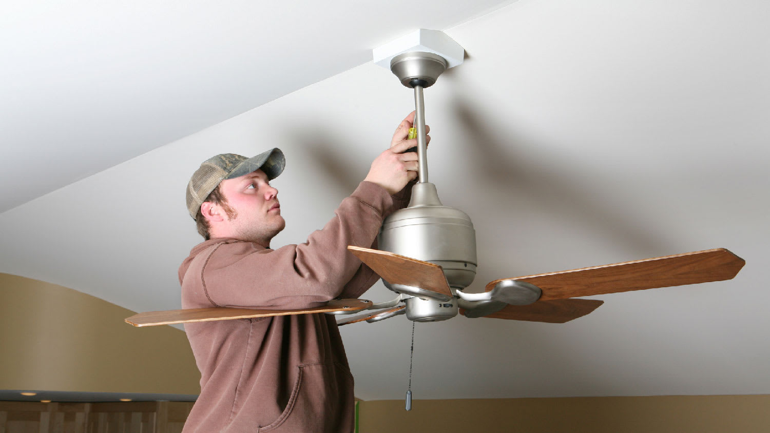 A man installing a ceiling fan mounting bracket