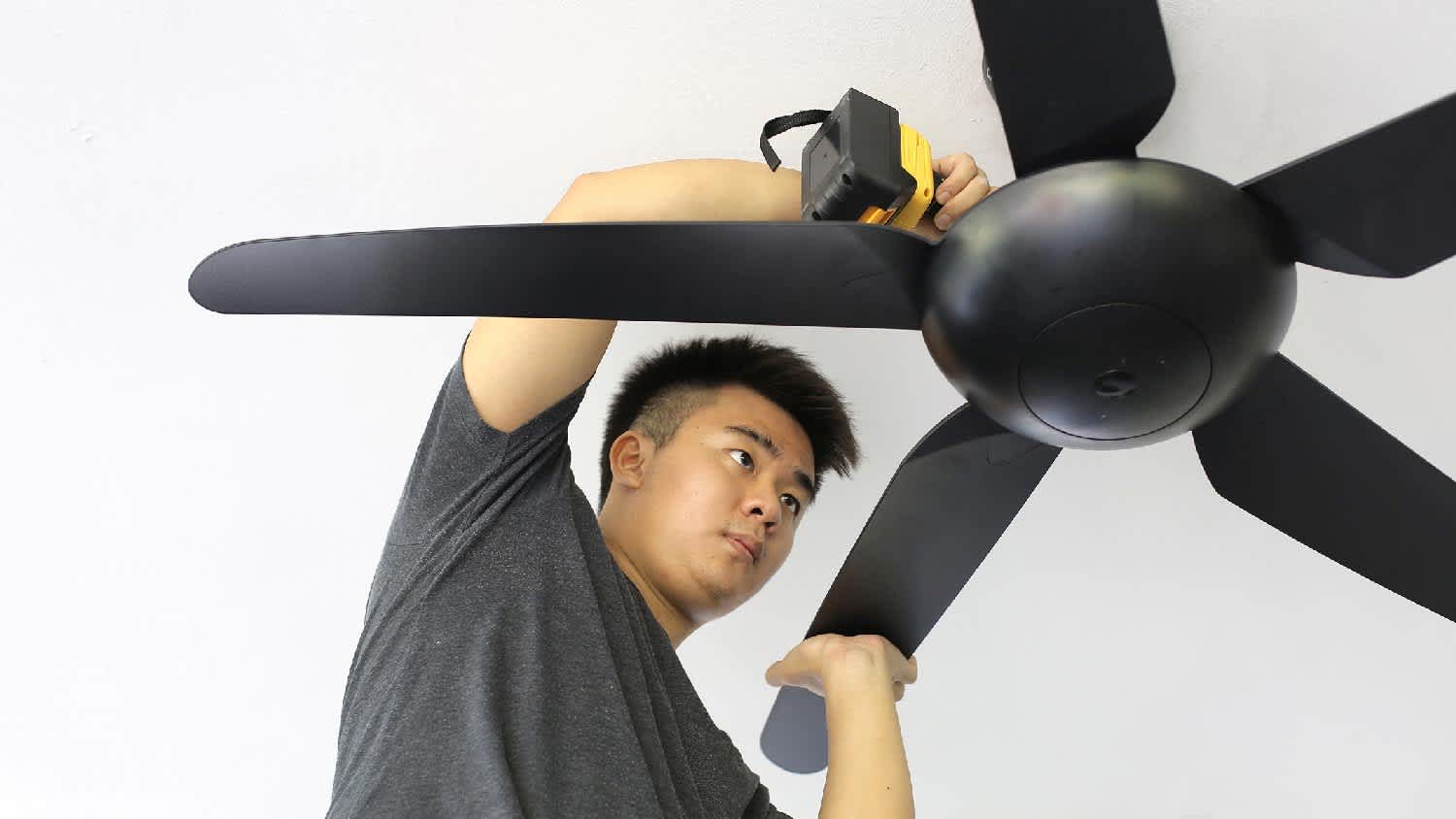 A man tightening a ceiling fan mounting bracket