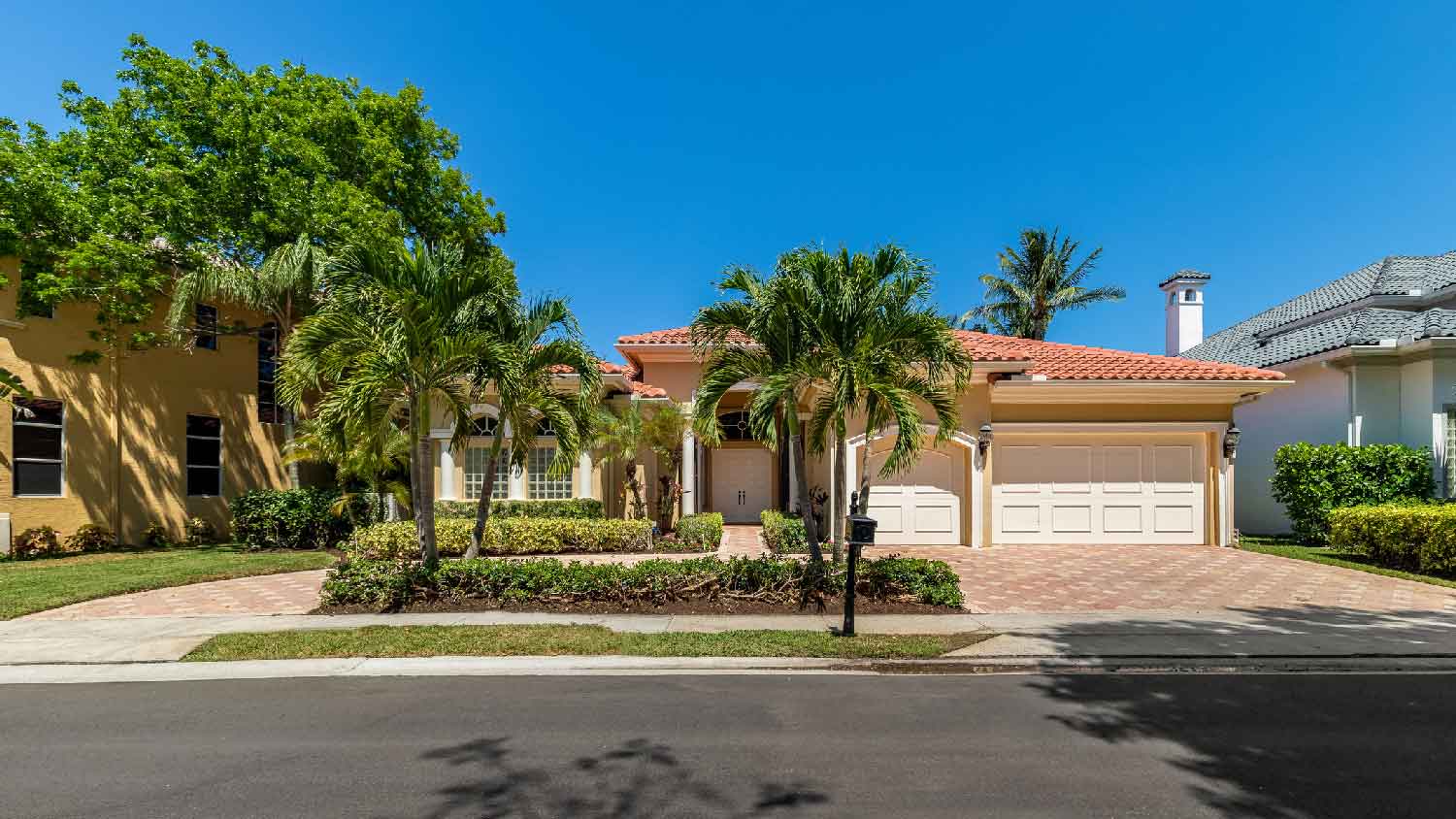 The facade of an elegant house with palm trees in its front yard