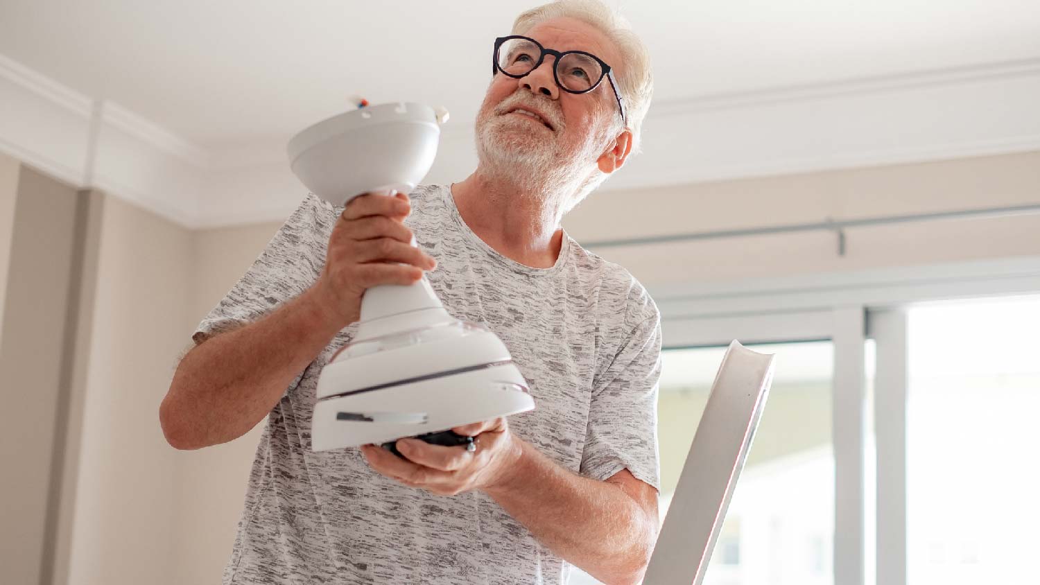 A man ready to mount a ceiling fan bracket
