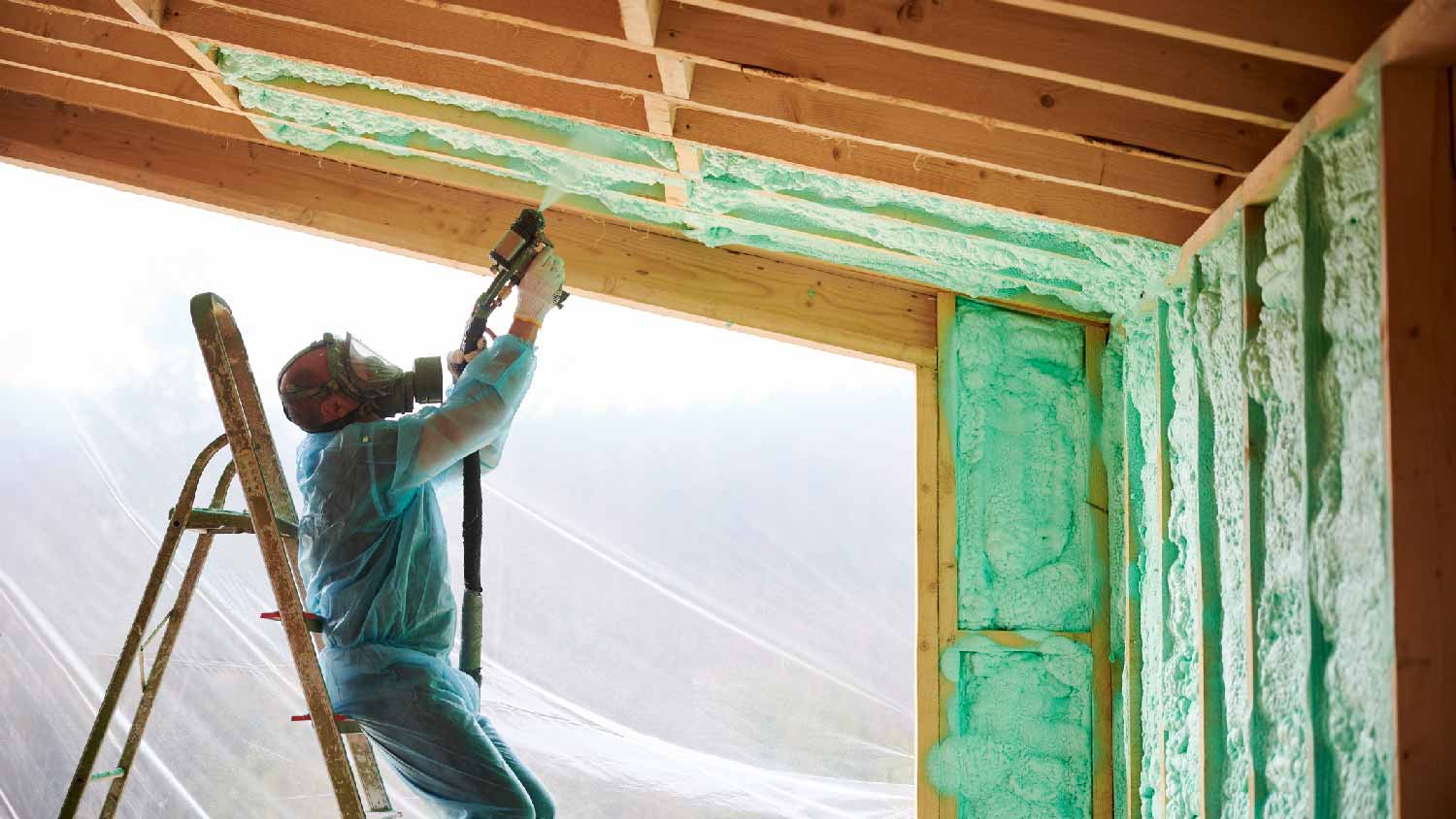 A professional spraying foam insulation on the ceiling