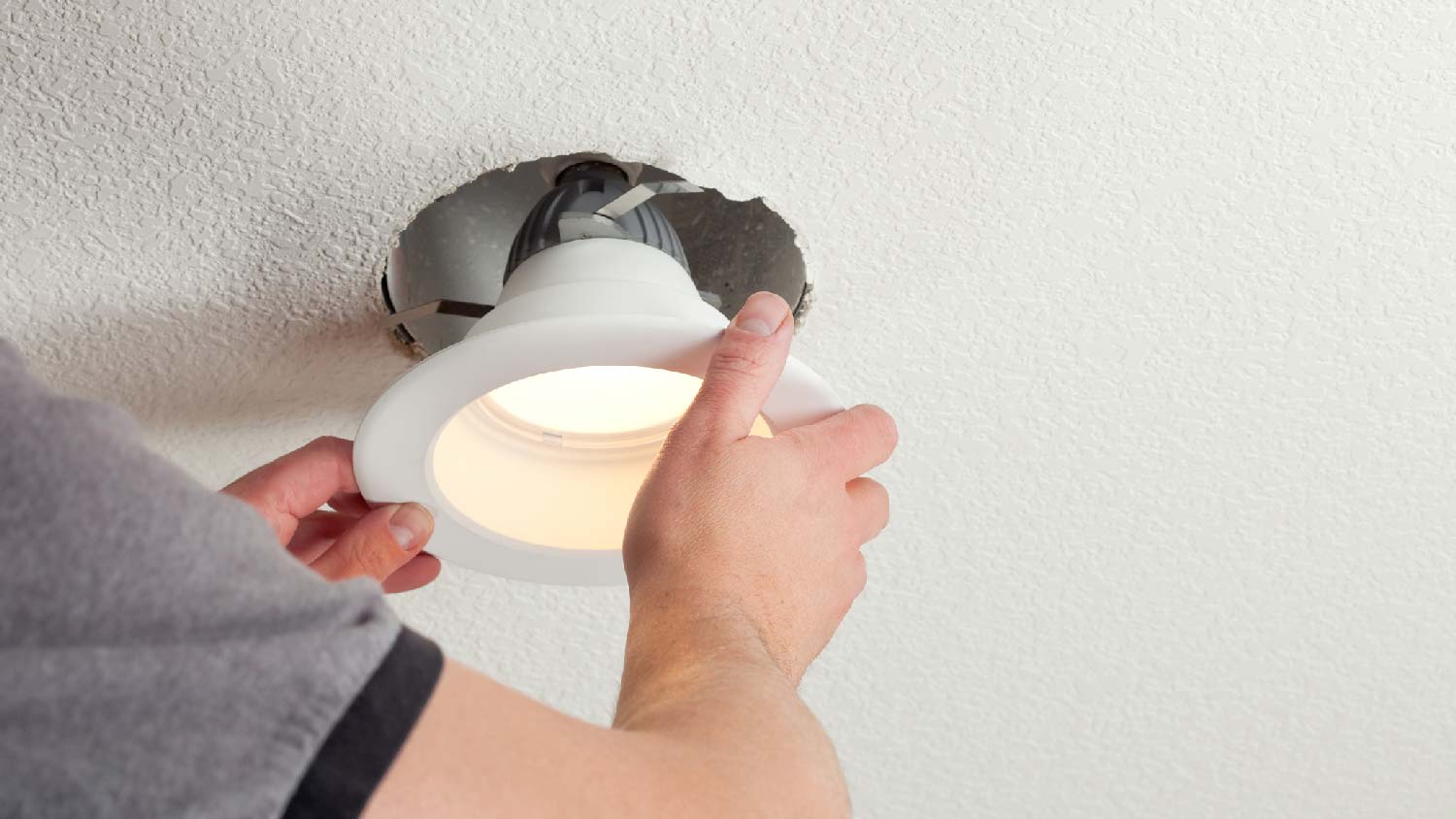 A man installing a can light