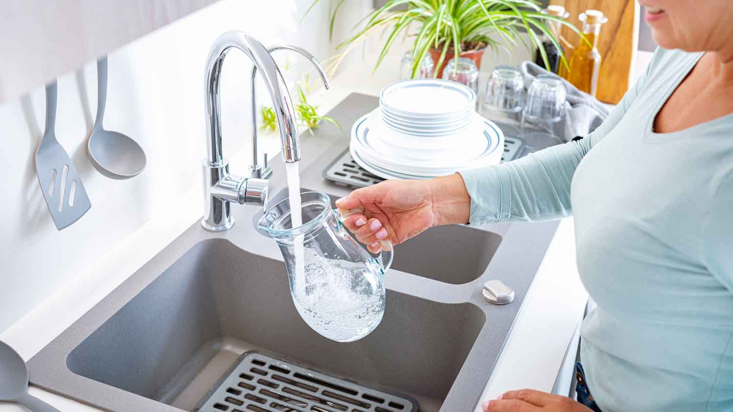 Woman filling jug with tap water
