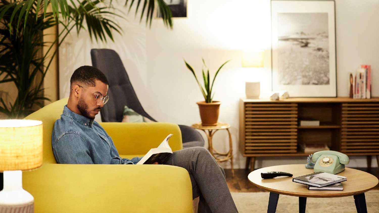 A young man reading a book on his sofa