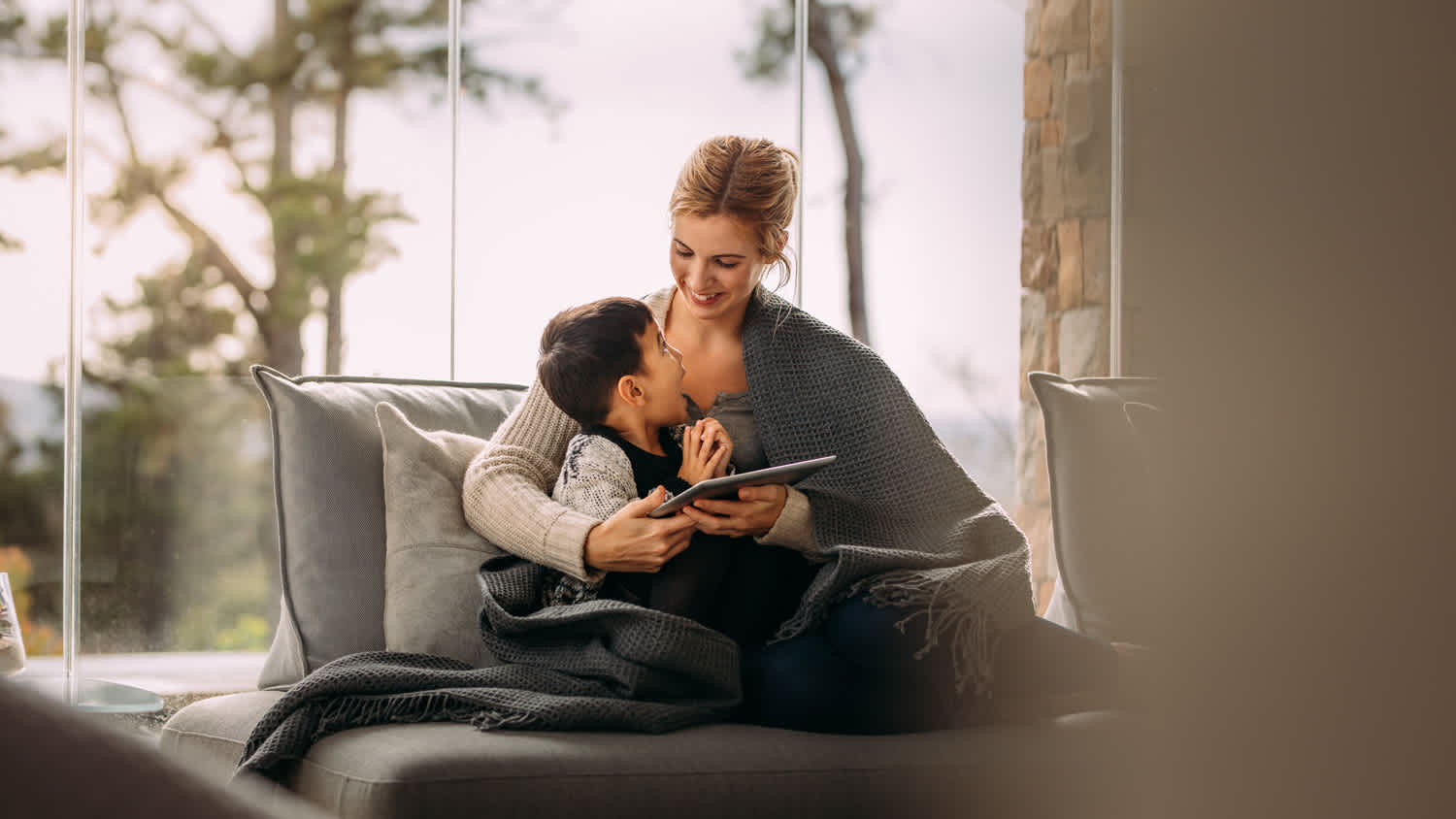 A mother and her son laughing while covered in a blanket