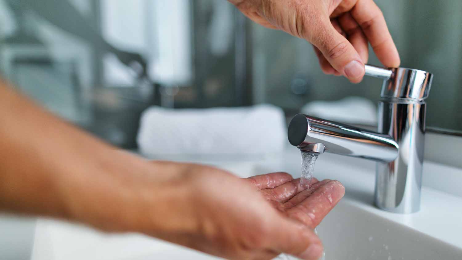 Man washing hands in bathroom sink
