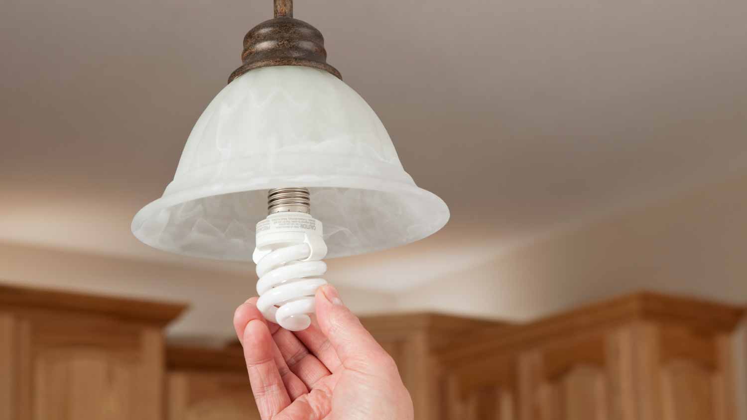 Woman installing fluorescent light bulb