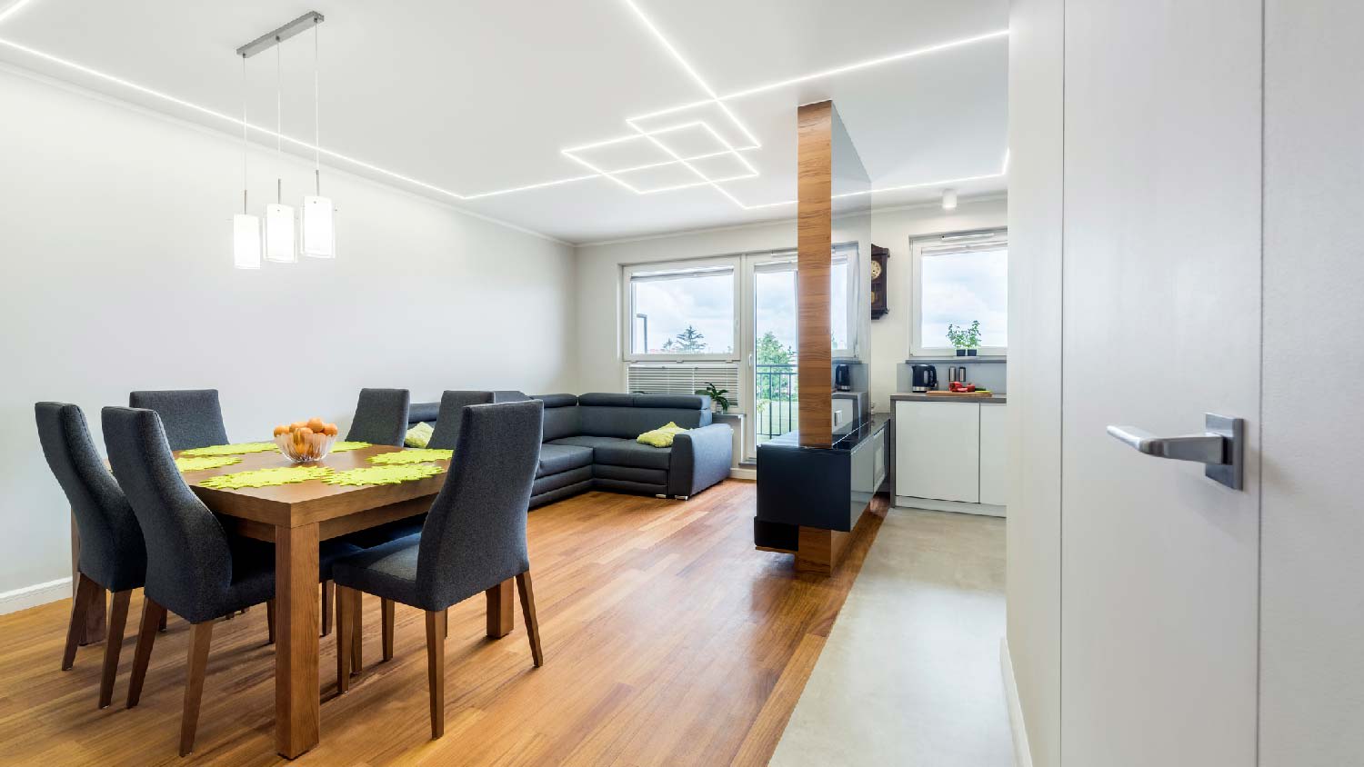 A living room with pendant track lighting over dining table