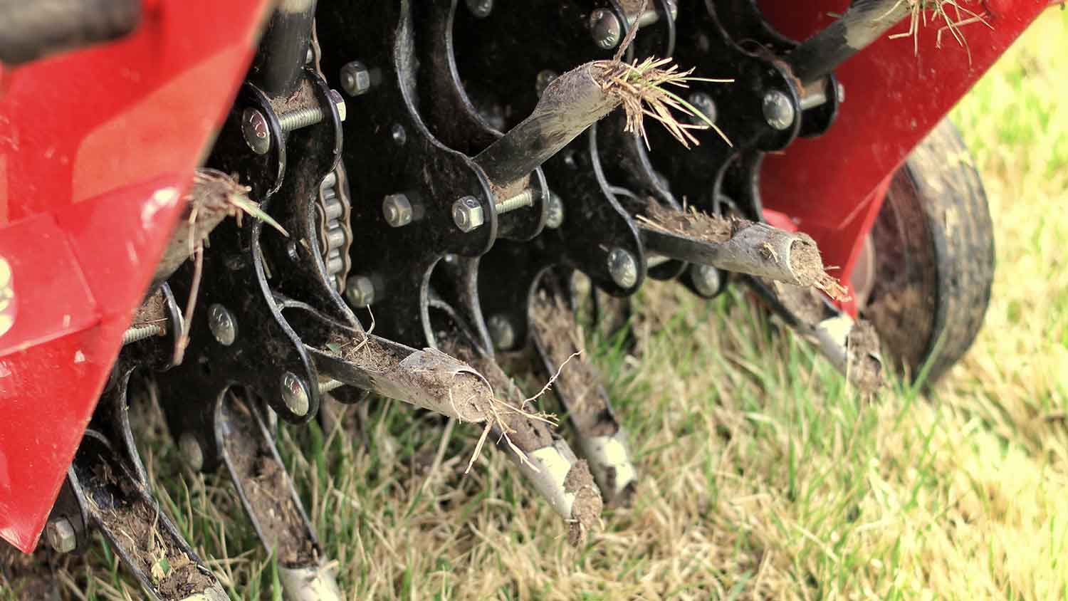 Breaking up compacted soil with an aerator machine