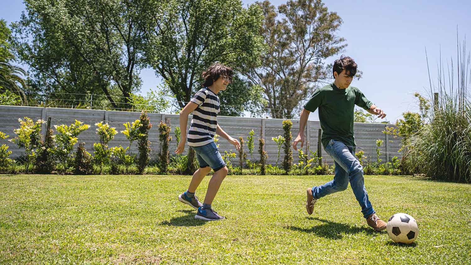 Siblings playing soccer in the yard