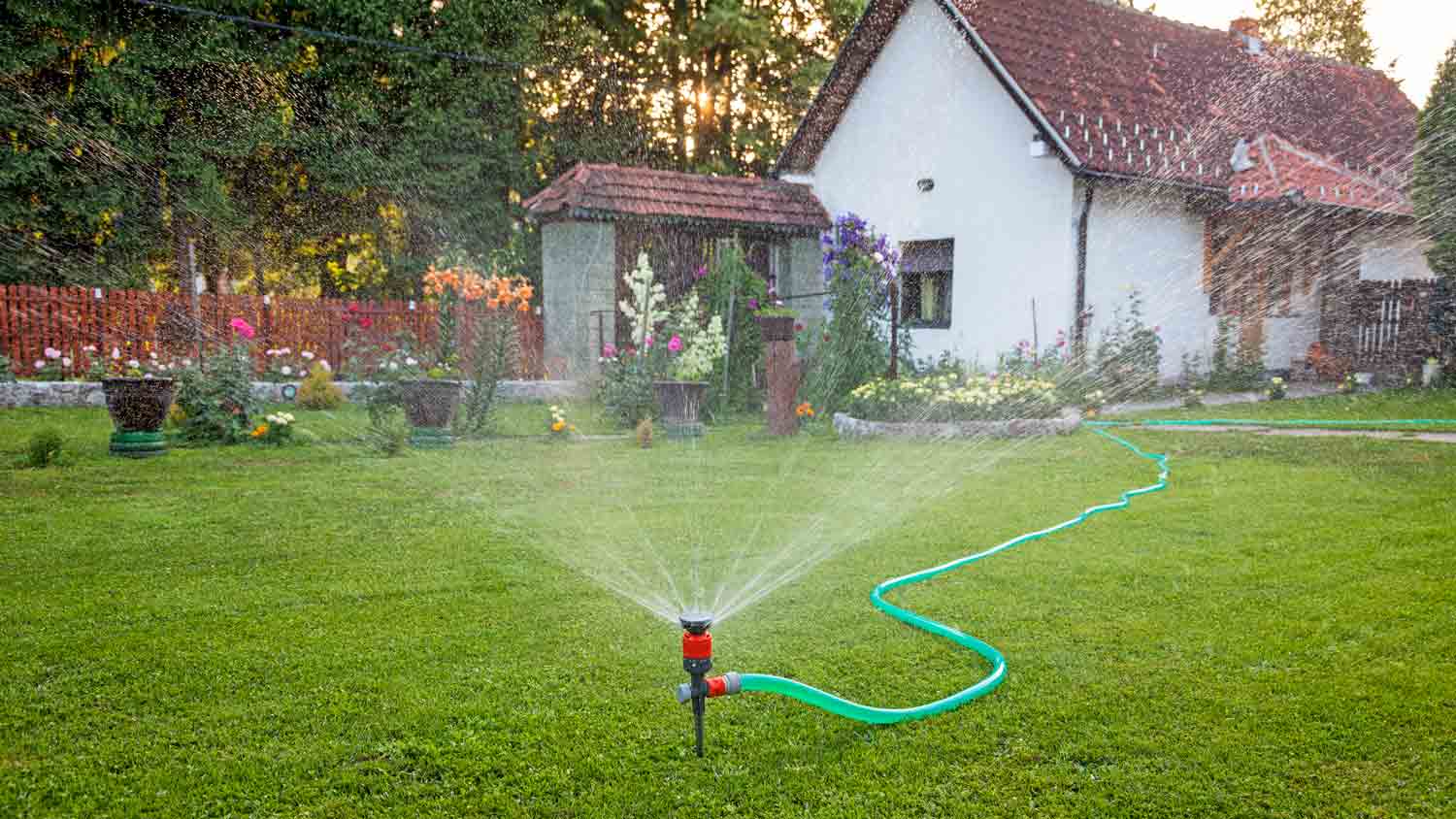 sprinkler watering garden in front of house