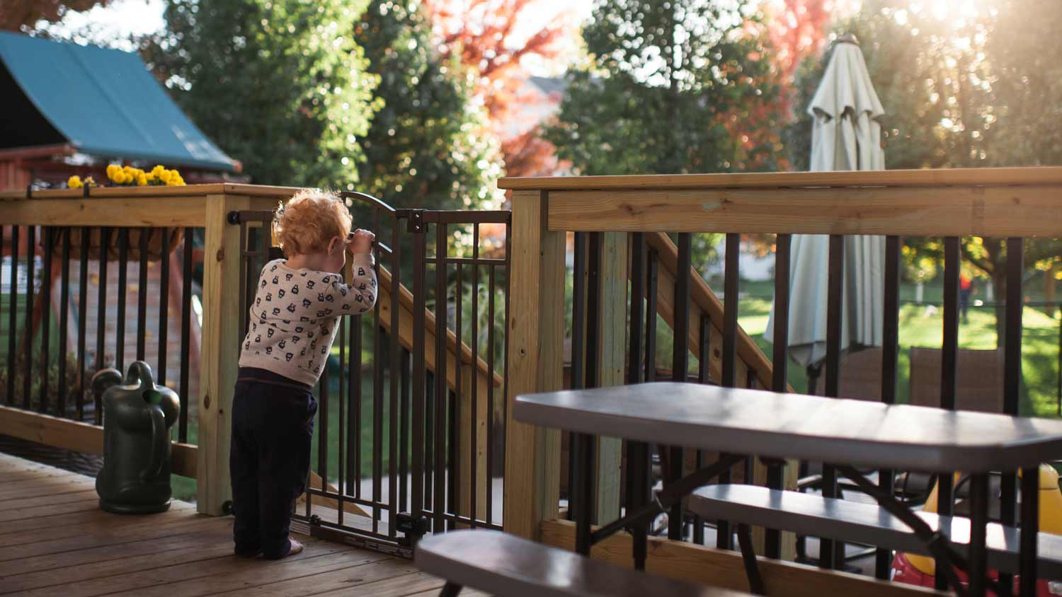 toddler looking out over the deck gate