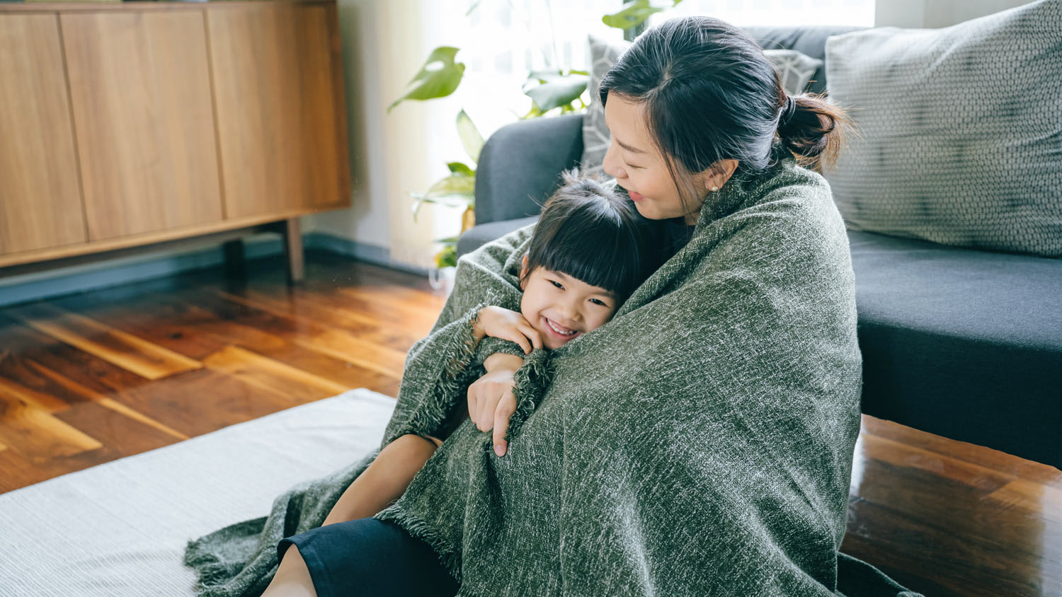 Young mother and daughter wrapped in blanket