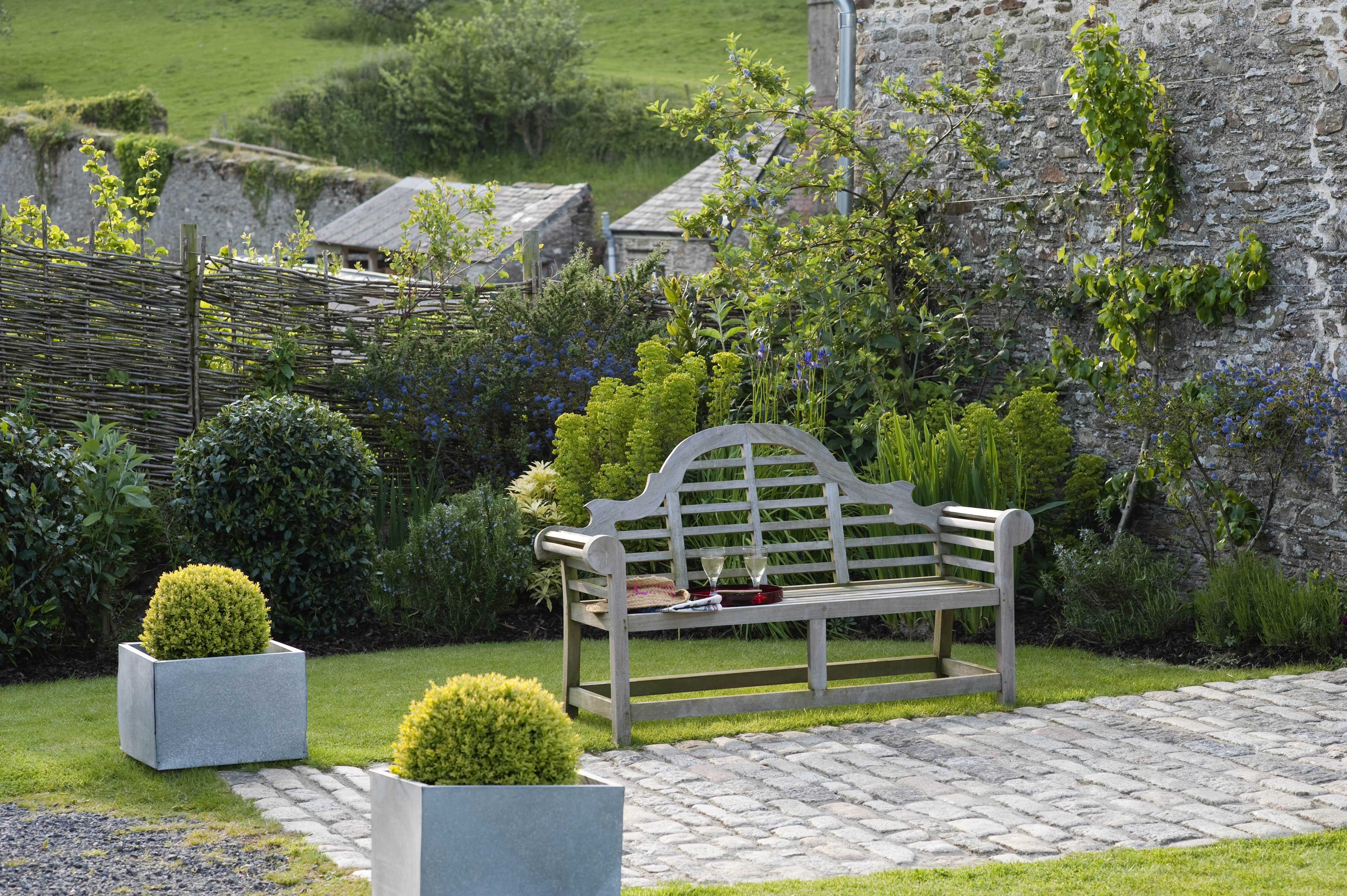 Historic farmhouse garden with bench enclosed with a wattle fence