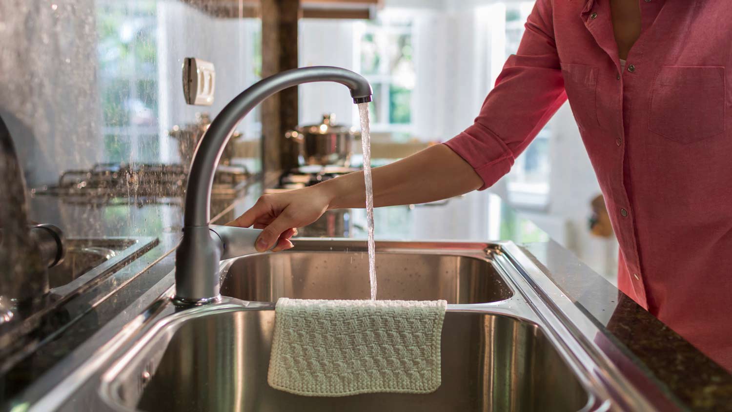 woman turning on faucet in kitchen