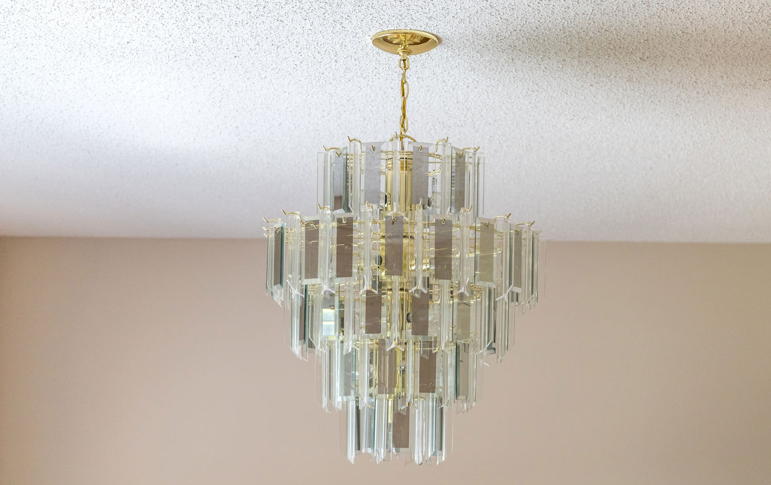 A retro glass chandelier hanging from a popcorn ceiling