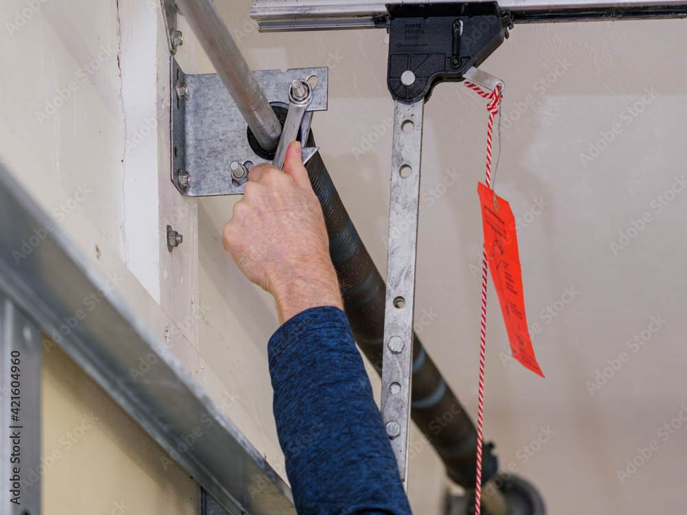 A person adjusting garage door torsion spring