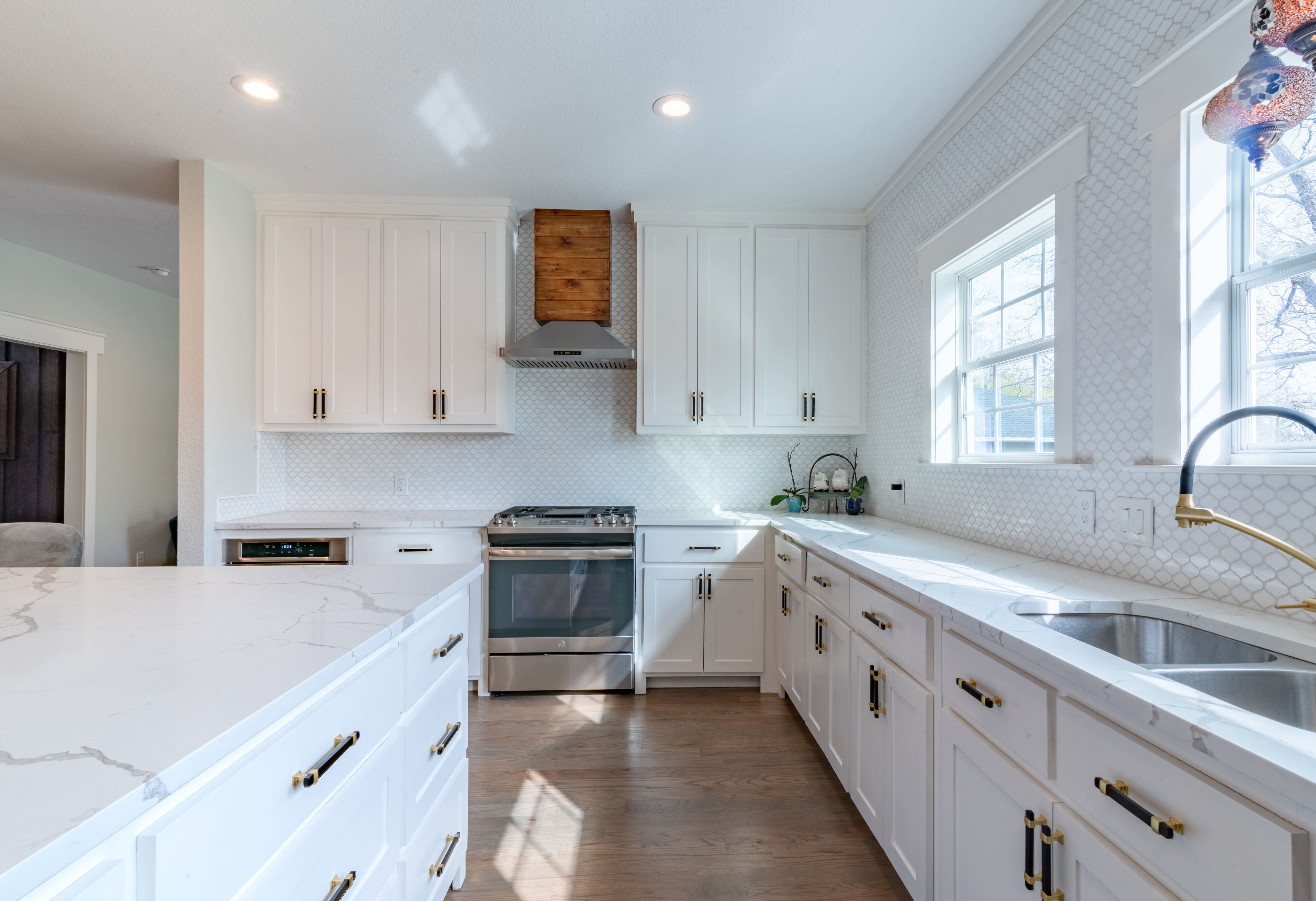 All white kitchen with gray and white quartz countertops and white fish-scale tile backsplas