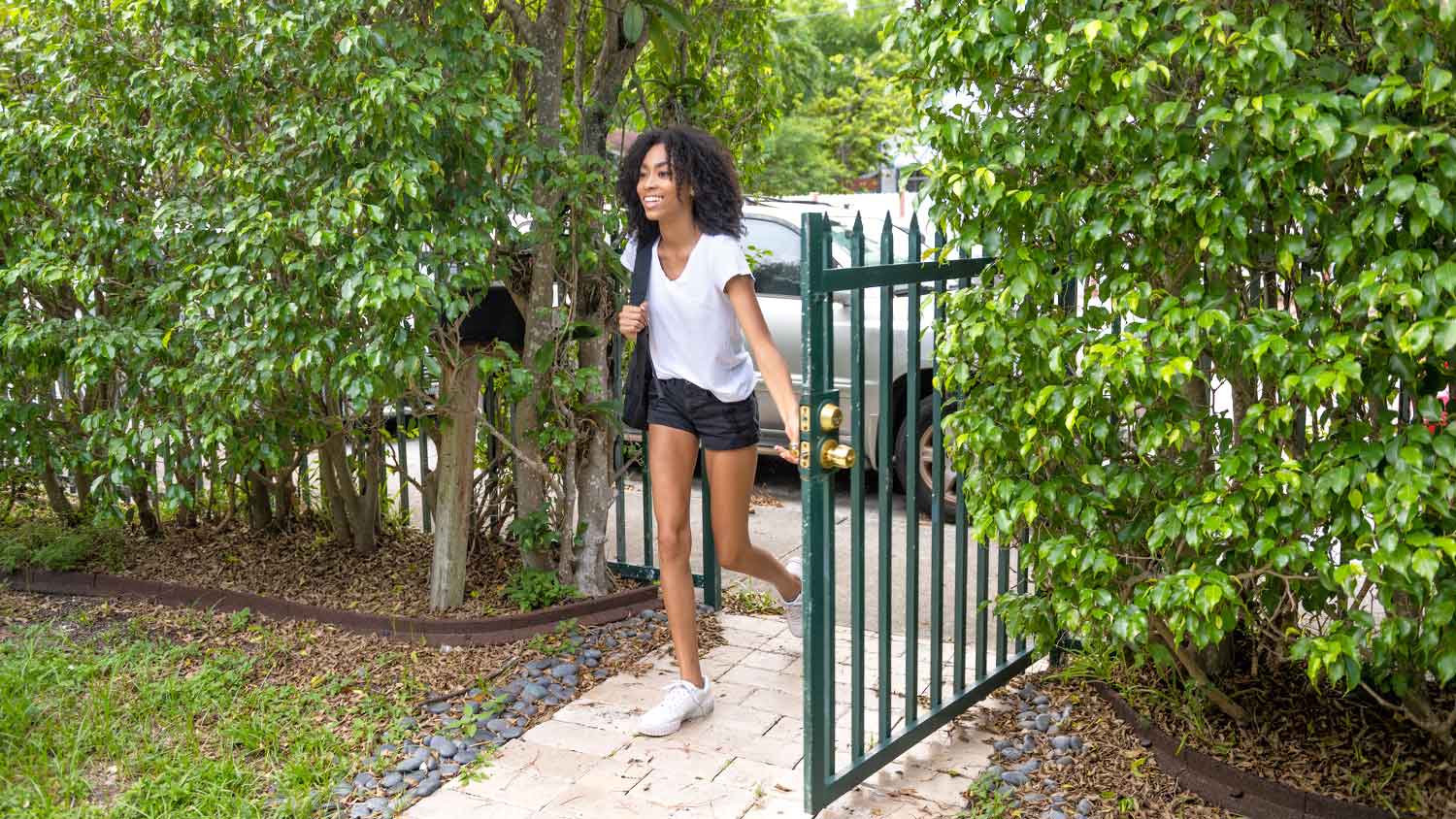 Teenage girl opening front yard gate