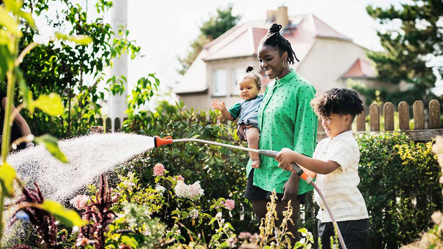 Son helping mom watering the garden