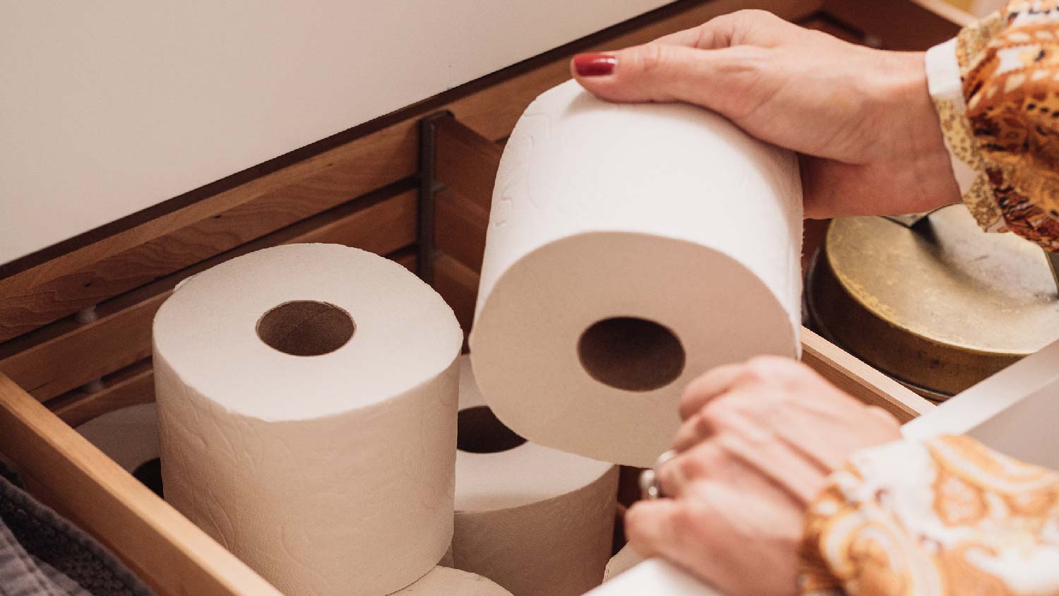 A woman picking up a toilet paper roll