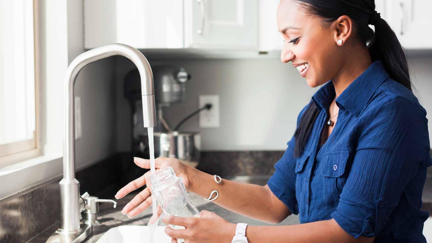 Woman washing baby bottle in kitchen
