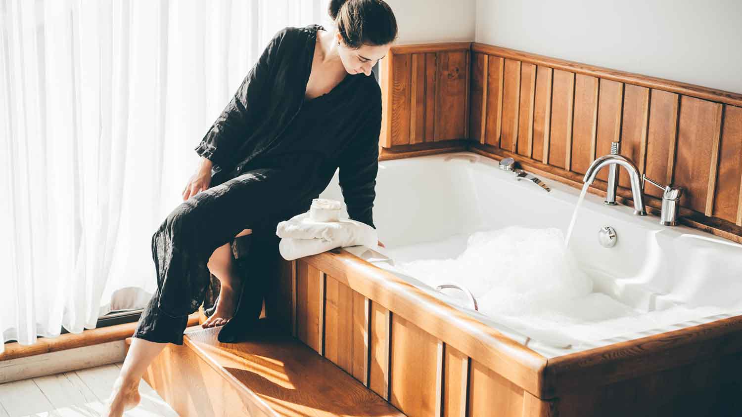 Woman wearing pajamas filling bathtub with water