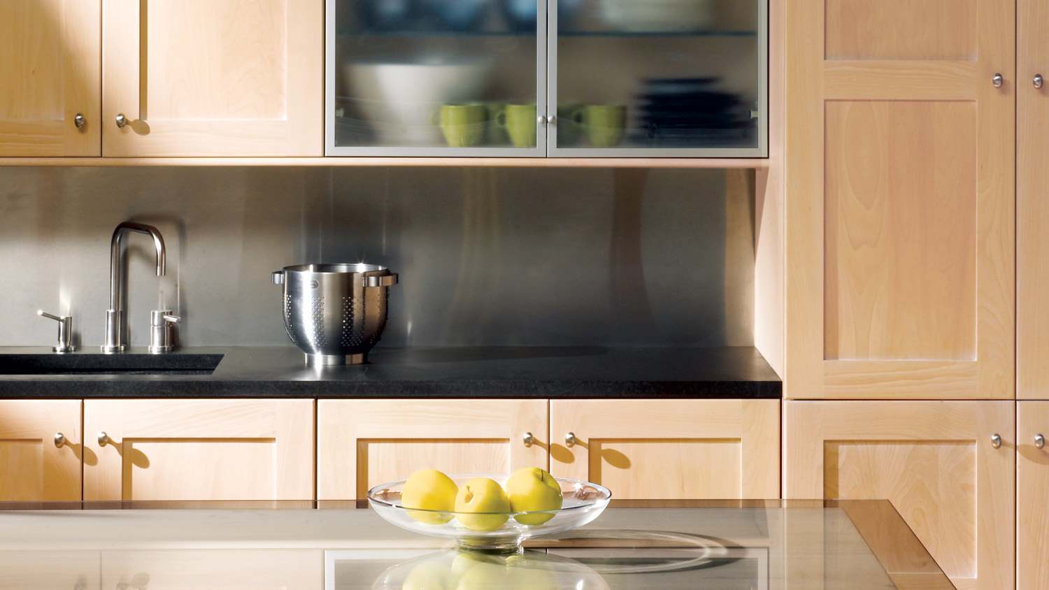 A kitchen with wooden cabinets and a black soapstone countertop