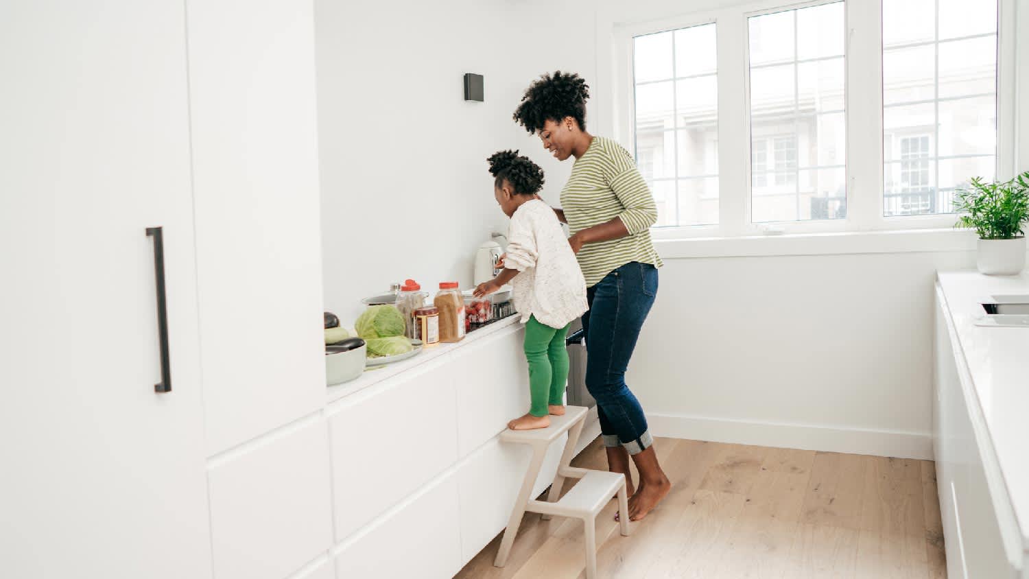 A mother with her kid preparing a meal on the kitchen countertop