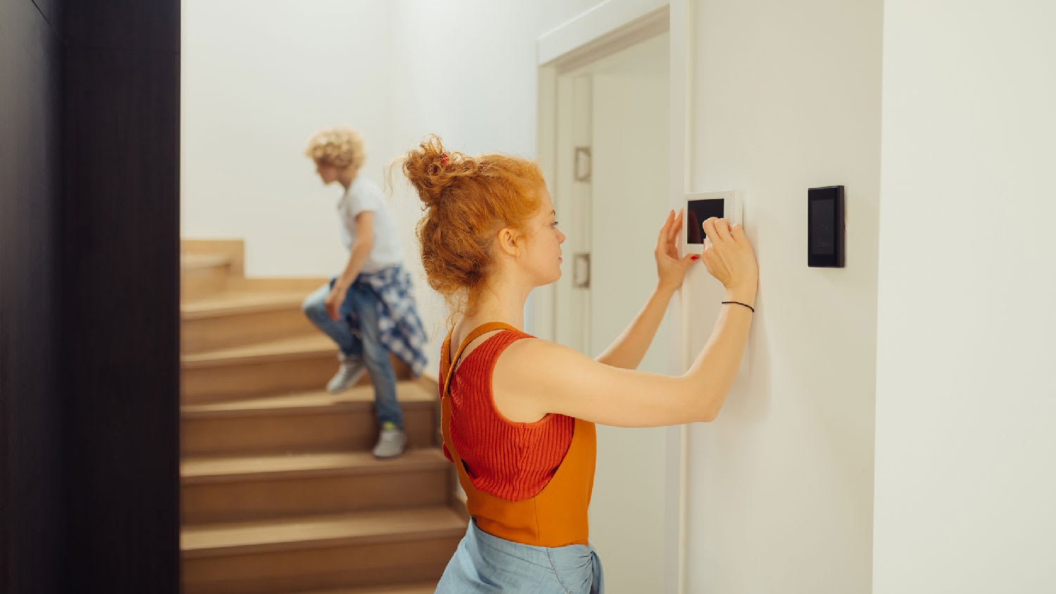 A young woman turning on a thermostat