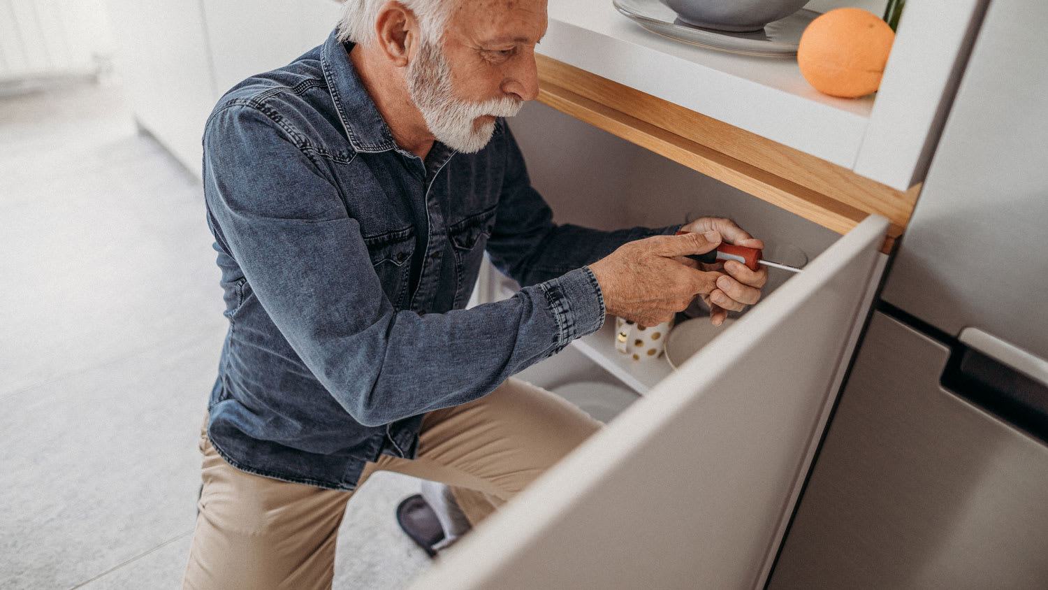 Man using tools to fix cabinets