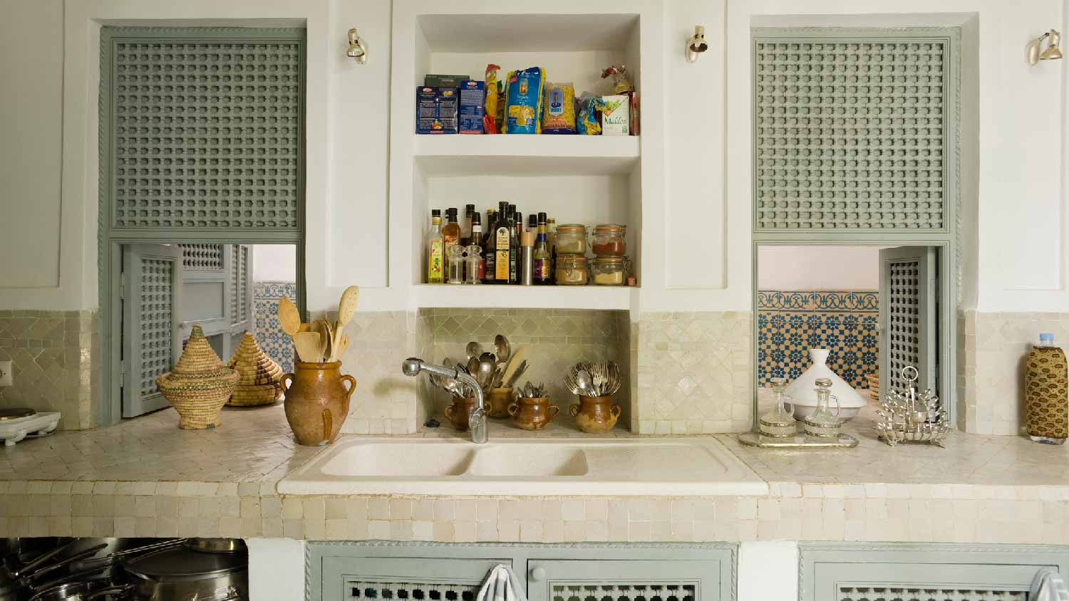 A kitchen with tiled countertop and recessed shelving