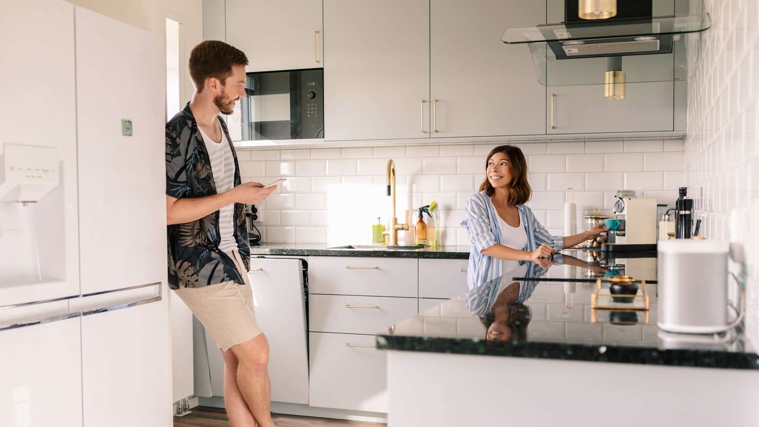 A couple talking in the kitchen while woman making coffee