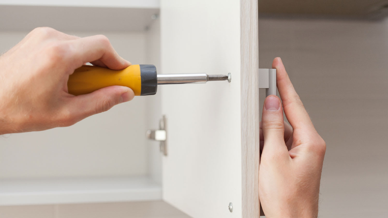 A woman installing cabinet hardware