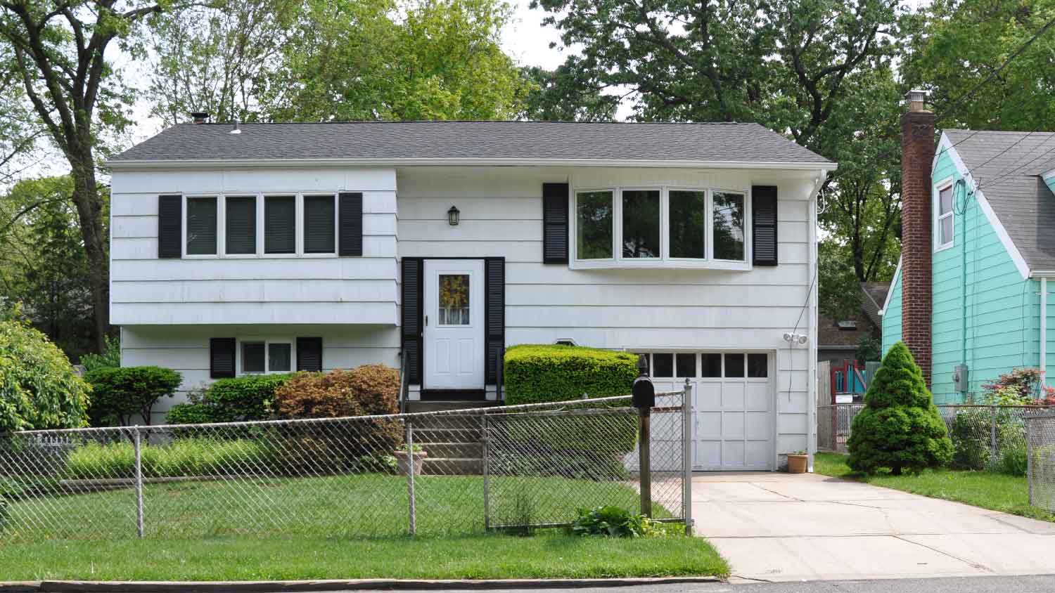 A suburban house with chain link fence on the front lawn