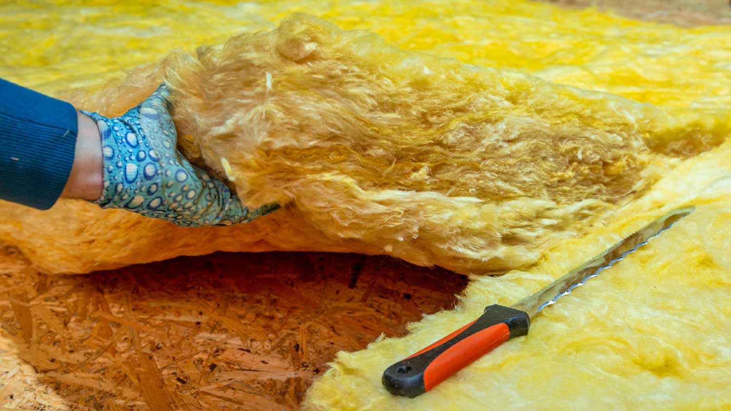 A professional removing a fiberglass insulation