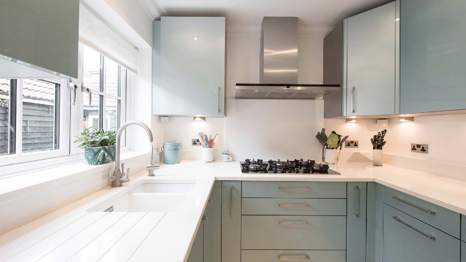 A white quartz countertop in a kitchen with green cabinets