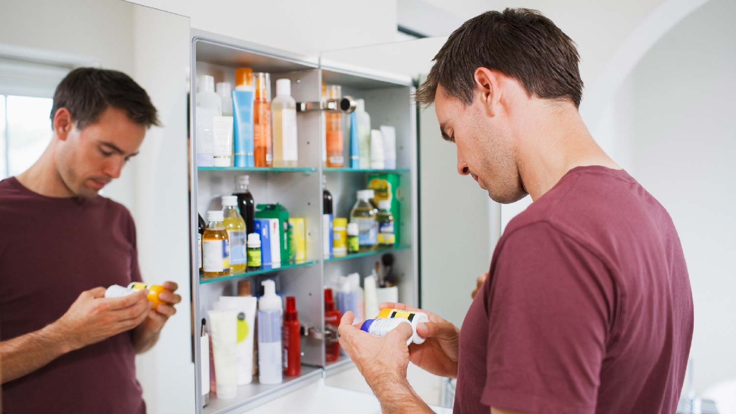 A man looking at bottles in a medicine cabinet