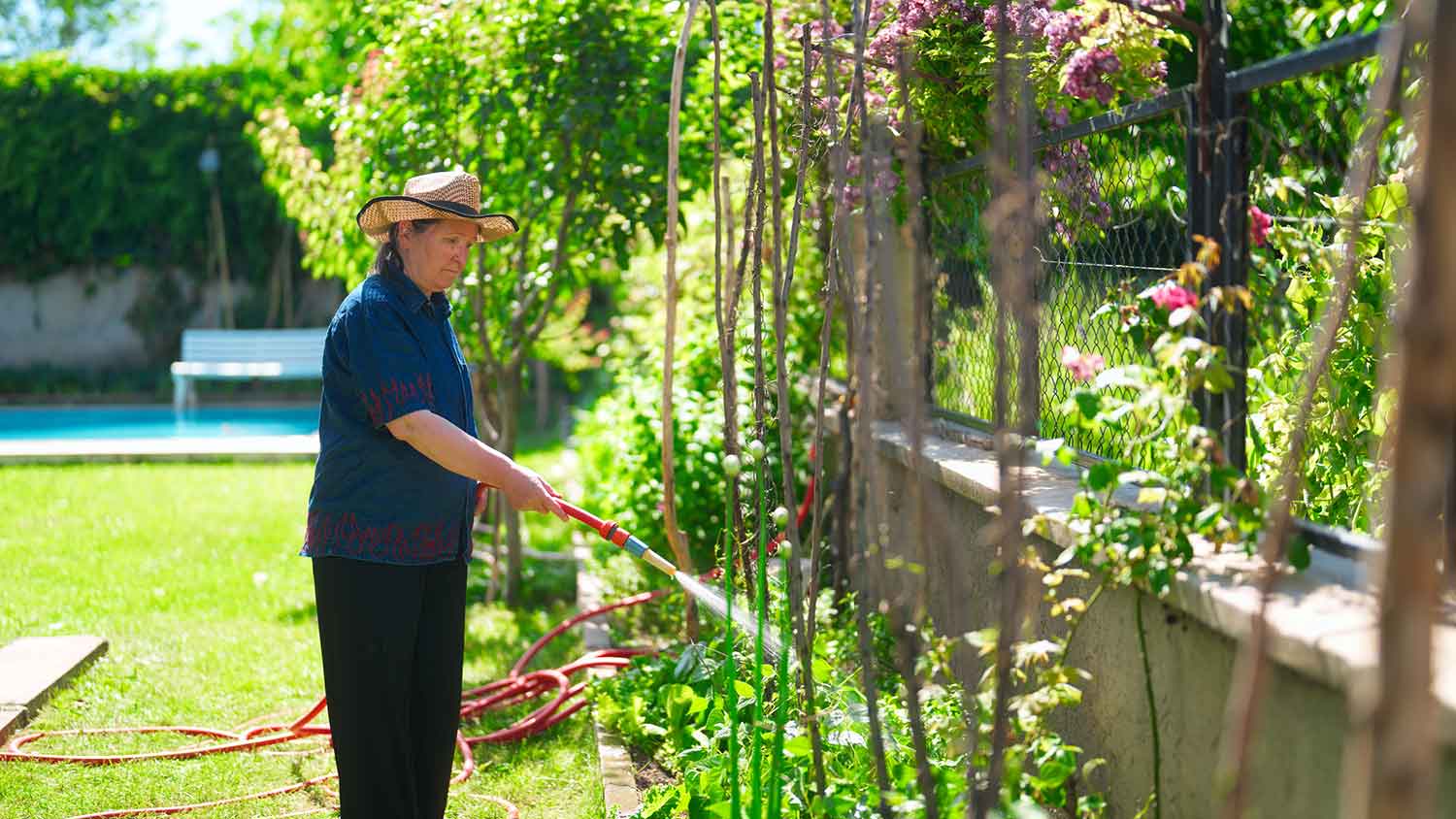 Woman using garden hose to water the yard