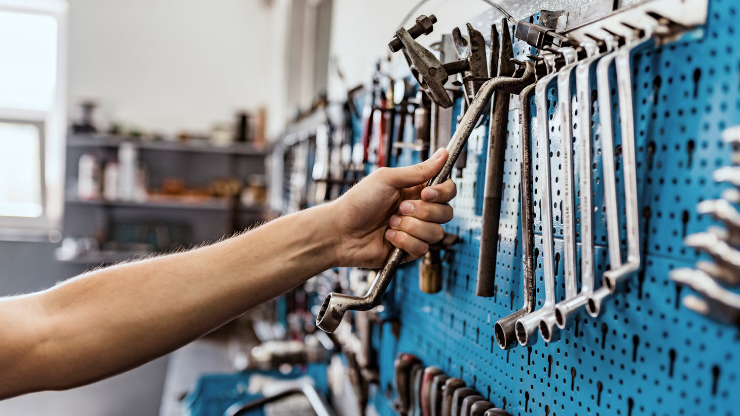 A male’s hand reaching for a tool in garage workstation